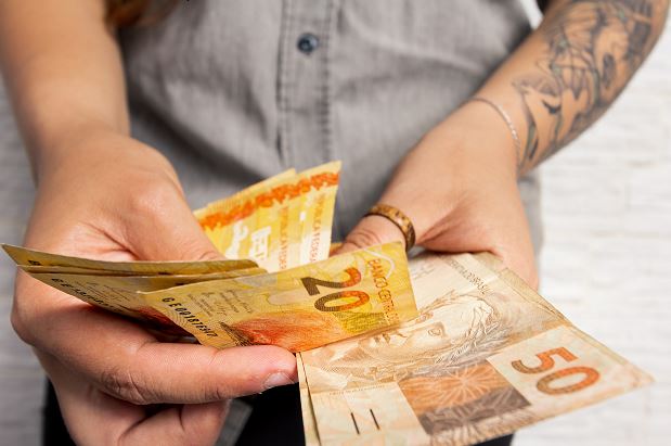 Bras Tatoués Et Mains Qui Donnent Une Petite Liasse De Billets