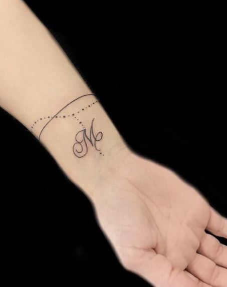 Tatouage Poignet Femme Initiale Suspendu à Un Bracelet 