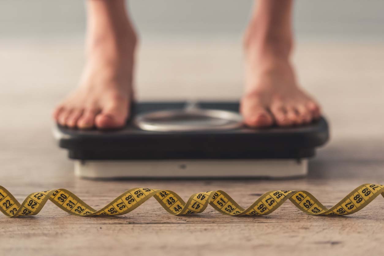 femme sur une balance avec un ruban à mesure