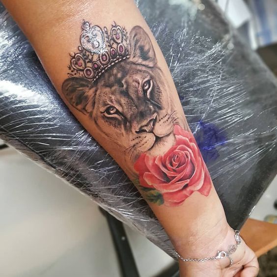 Tatouage De Rose En Couleur Avec Une Reine Lionne Sur L'avant Bras
