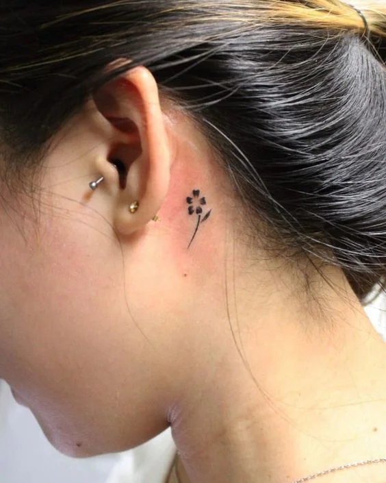 tatouage Fleur noire minimaliste derriere l'oreille