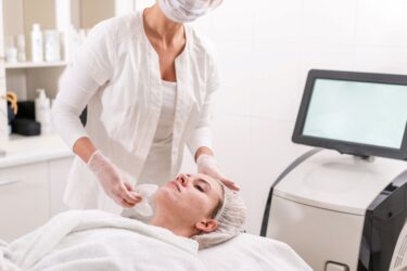 médecin appliquant produit de peeling sur le visage d'une patiente