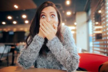 Femme choquée couvrant sa bouche assise dans un restaurant