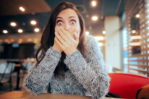 Femme choquée couvrant sa bouche assise dans un restaurant