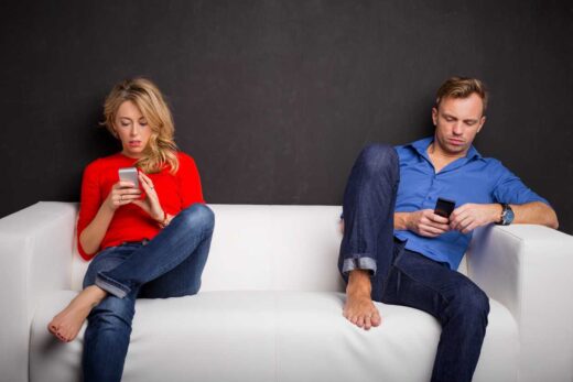 Couple assis sur un canapé avec leur téléphone dans la main
